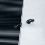 Par de câmeras de segurança CFTV modernas instaladas em parede de prédio comercial - Nunes Consultoria Informática