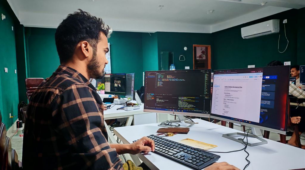 Análise e Desenvolvimento de Sistemas Desenvolvedor programando um sistema sob encomenda em múltiplos monitores
